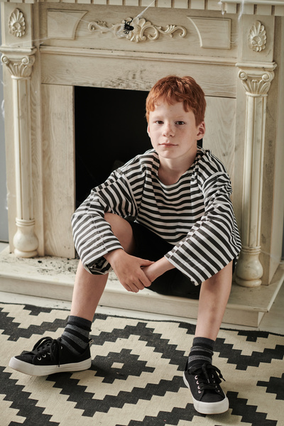 Boy in Pirate Costume Sits against Background of Fireplace